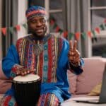 Nigerian Proverbs: A man expressing himself with smiles while playing a traditional African drum